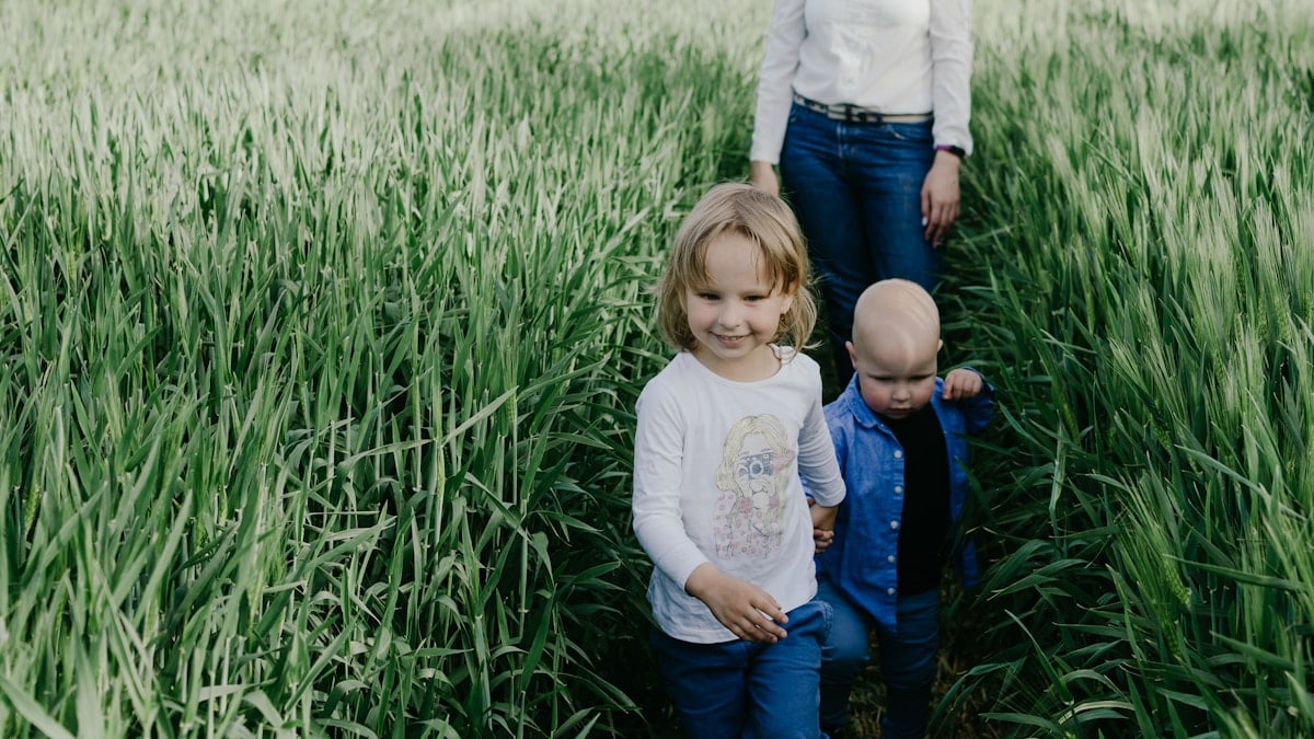 girl in white long sleeve shirt and blue denim jeans sitting on green grass field during
